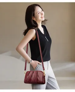 Detailed view of dark burgundy pleated leather cross-body bag with gold-tone hardware