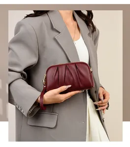 Close-up of burgundy leather clutch bag with pleated texture and gold zipper detail