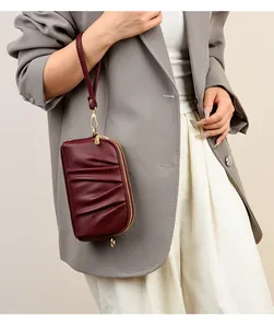 Wrist view of a wine red lychee leather clutch bag with elegant pleated texture detail