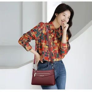 Elegante borsa a tracolla bordeaux con trama litchi e tracolla regolabile su modella