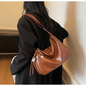 Detalle del bolso hobo de cuero marrón caramelo con borla de cordón y etiqueta de marca