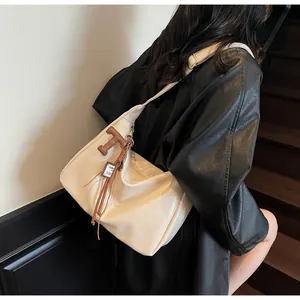 Detalle de bolso hobo blanco roto con colgante de cuero marrón y borla de flecos