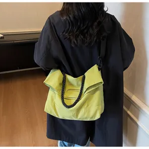 Close-up of a neon yellow tote bag with black woven rope handles and adjustable strap