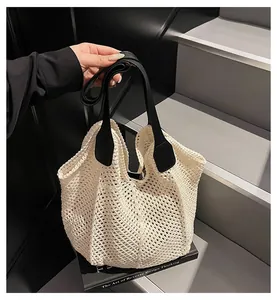 Detailaufnahme der weißen Häkeltasche mit Netzstruktur und schwarzen Ledergriffen