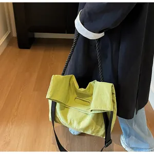 Close-up of lime green tote bag with black woven handles and nylon texture detail