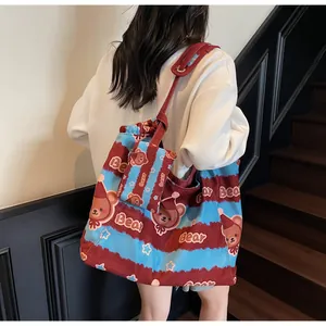 Dettaglio borsa tote in tela con stampa orso e mini pochette coordinata sulla spalla