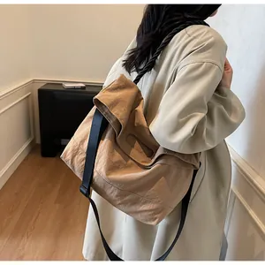 Detail of khaki tote bag featuring fold-over top with cutout handle and wide black strap