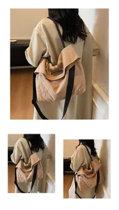 Detail view of large beige canvas tote bag showing textured fabric and wide black strap