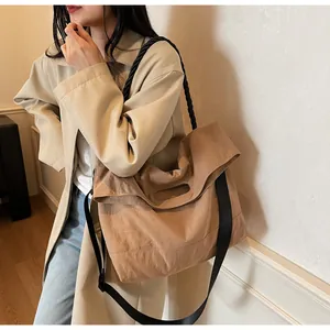 Detail view of khaki tote bag featuring black woven rope handle and wide nylon strap