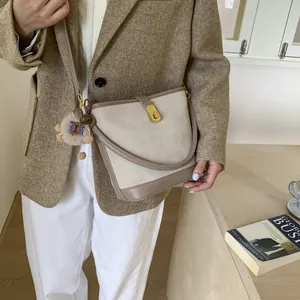 Retro faux suede bucket bag in cream and khaki with a plush charm and gold buckle