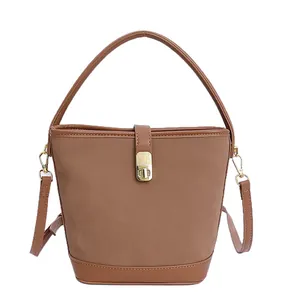 Brown faux suede bucket handbag with gold twist lock and adjustable shoulder strap