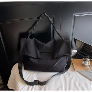 Close-up of black nylon tote bag featuring braided handle and adjustable shoulder strap
