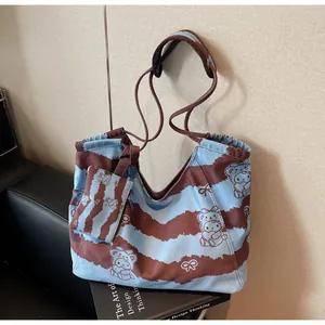 Dettaglio della borsa tote in tela azzurra con disegni cartoon e mini borsellino