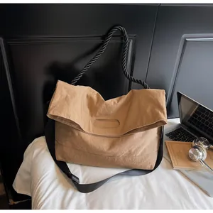 Detail of a large khaki tote bag with adjustable shoulder strap and thick woven handle