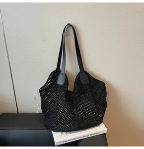 Detail der schwarzen Häkeltasche mit weißem Kordelzug auf einem Ledersessel