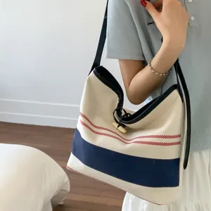 Striped canvas tote bucket bag for beach travel shown in a stylish side view on model
