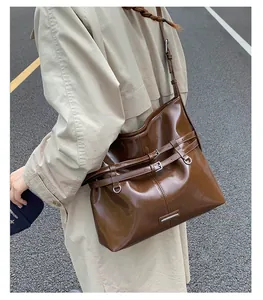 Detail der dunkelbraunen Leder-Shopper-Tasche mit Vintage-Schnallenriemen an der Schulter