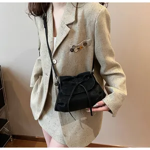 Nahaufnahme der schwarzen Umhängetasche mit Schleife auf einem Khaki-Tweed-Blazer