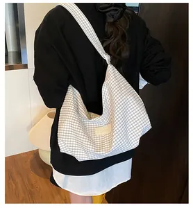 Detail shot of a large black and white checkered tote bag with adjustable strap and logo