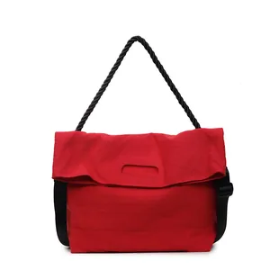 Minimalist red oversized tote bag with black braided rope handle and flap closure design