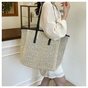Detail of a large woven straw tote bag with black trim and handles on a model