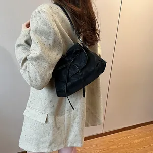 Minimalistische schwarze Leder-Unterarmtasche mit Schleife, an einem Modell gezeigt
