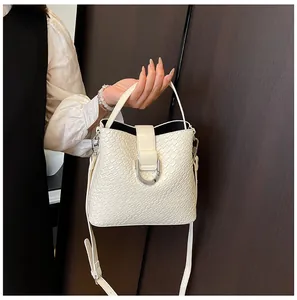 Detail der cremefarbenen Beuteltasche mit Webstruktur, D-Ring-Schnalle und Riemen