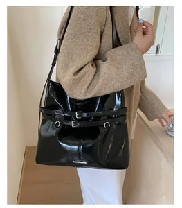 Detailansicht der schwarzen glänzenden Schultertasche mit Silberschnallen am Wollmantel