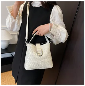 Detail der weißen Eimer-Tasche mit Webstruktur, silberner U-Schnalle und Umhängegurt