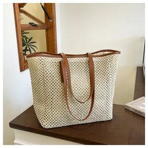 Detail of woven mesh texture and brown leather strap on cream straw tote bag