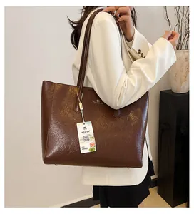 Detailed view of large brown oil-wax leather tote bag worn on a woman's shoulder