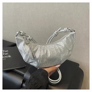 Detail der silbernen Metallic-Sichelbag mit Falten, Knotengriff und Quasten-Anhänger