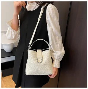 Detail der cremefarbenen geflochtenen Beuteltasche mit Hufeisenschnalle am Modell