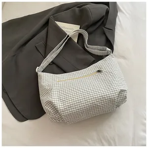 Close-up of checkered hobo bag with front zipper pocket on a minimalist background