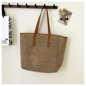 Close-up of woven straw tote bag featuring brown leather handles and natural texture