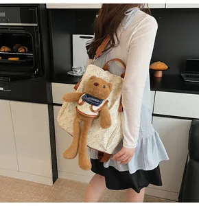 Detail of cream backpack featuring bear patterns and a plush brown bear accessory
