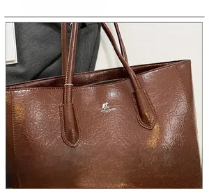 Detailed view of the brown wrinkled leather texture and silver logo on the tote bag