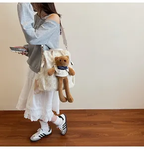 Detailed view of white backpack with yellow bear prints and brown plush toy charm