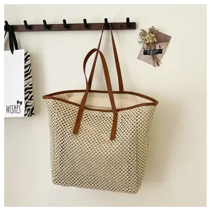 Detail of woven straw tote bag featuring brown leather trim and dual handle design
