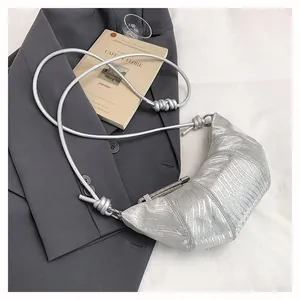 Detailansicht der silbernen Croissant-Tasche mit Wellenstruktur und geknotetem Schultergurt