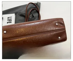 Close-up of brown leather tote bag bottom with four silver metal protective feet