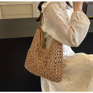 Détail du motif ajouré tissé à la main et de la bandoulière en cuir brun sur le sac de paille