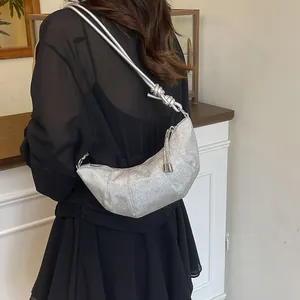 Silberne sichelförmige Tasche mit Glitzereffekt und Quasten-Detail am Frauenmodell