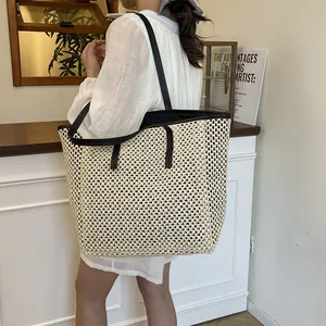 Large woven straw tote bag with black leather trim and handles for beach or travel