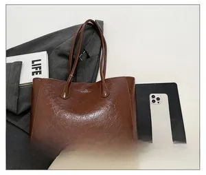 Detail of brown tote bag showing textured leather, metal logo, and interior capacity