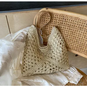 Détail de la texture tissée ajourée et des anses en similicuir marron sur un sac d'été