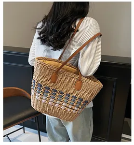 Detail of handwoven straw tote featuring colorful striped bottom and leather handles