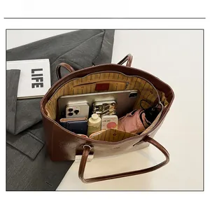 Detailed capacity view of brown leather tote bag with tablet, umbrella, and essentials