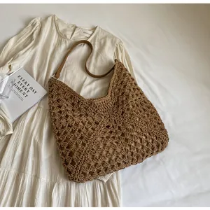 Détail d'un grand sac fourre-tout en paille marron avec tissage crochet et anses en cuir