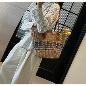 Detail of hand-woven straw tote with blue decorative bands and leather handles